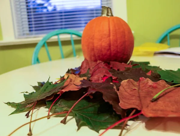 Citrouille avec des feuilles d'automne sur la table de cuisine les illustrant de la saison d'automne et le temps change — Photo