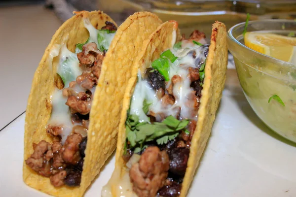 Tacos mexicanos alineados con carne, queso y cebollas verdes rematándolo —  Fotos de Stock