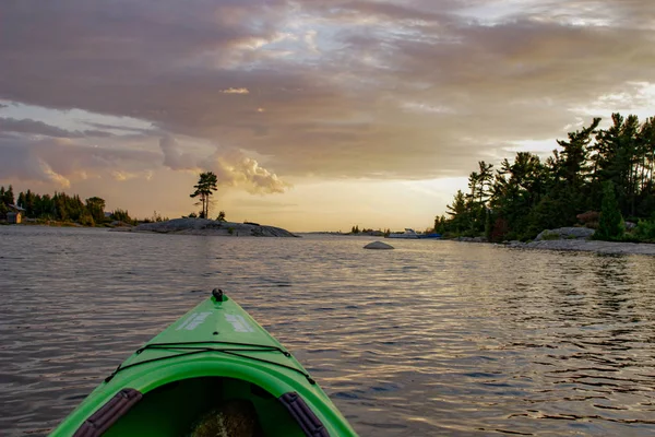 Faire du kayak sur une eau calme et paisible vers le coucher du soleil. Tourné du point de vue du pagayeur . — Photo