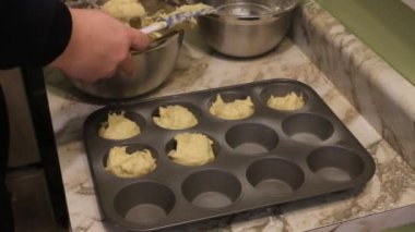 Hamur pasta çantasından fırın tepsisindeki kağıt bardak içine koyarak eller görünümünü yakın çekim.