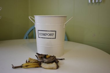 a labelled compost bucket with banana peels in front ready to be sorted. theme of sorting your rubbish into proper bins. clipart