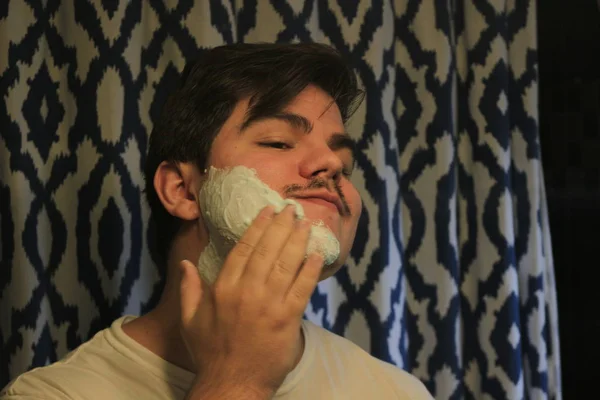 Adam 18-25 yaşında bir aynada tıraş — Stok fotoğraf
