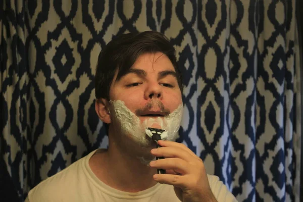 Man 18 to 25 years old shaving in a mirror — Stock Photo, Image