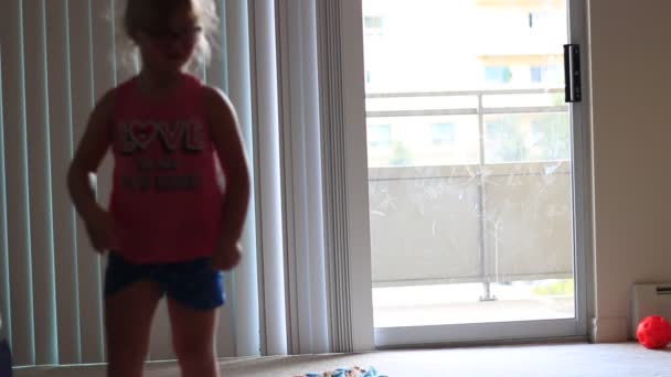 Маленький ребенок делает стойки на руках в гостиной дома, играет вокруг — стоковое видео
