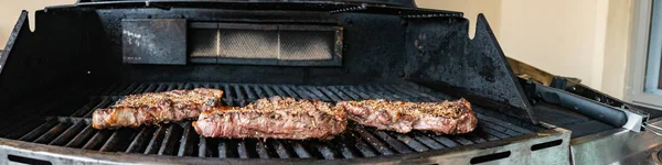 Filetes en la parrilla. Un buen par de jugosos filetes en la parrilla con marcas de parrilla, llamas y humo — Foto de Stock