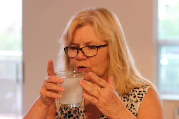 Seniora kvinnor dricker ett glas vatten eller annan vätska — Stockfoto