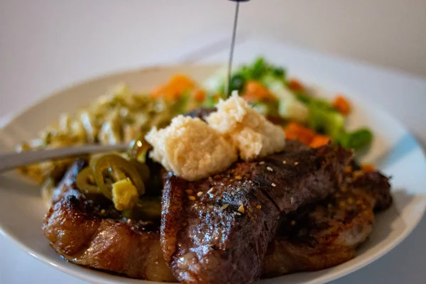 Közeli kilátás egy tányér szűzpecsenyét steak, közepes ritka, tálalva tészta és zöldség fehér háttér — Stock Fotó