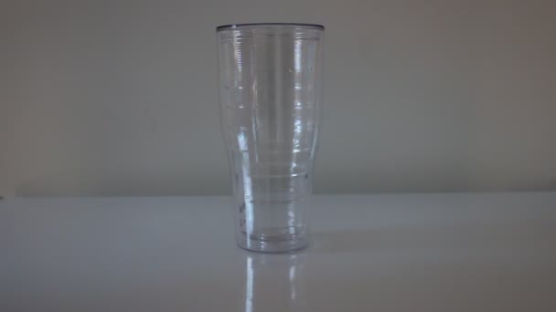 A close-up of a barista hand putting ice cubes into a plastic cup. A barman pouring ice from a pitcher into a takeaway cup that is standing on a bar counter with — Stock Video