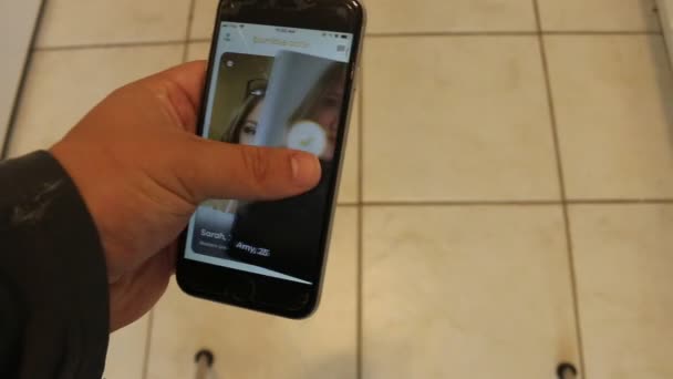 런던 캐나다, 9 월 29 2019: 자신의 휴대 전화에 범블 데이트 응용 프로그램을 통해 스 와이프 하는 사람의 편집 예시 비디오. 범블은 온라인 데이트 플랫폼입니다 — 비디오