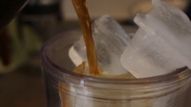 Barista, Cafe 'de kahve makinesini kullanarak Paket Buzlu Latte' ye kahve dolduruyor. Barista, kahve bardağını kahve bardağına dolduruyor. Profesyonel kremalı latte yapıyor..