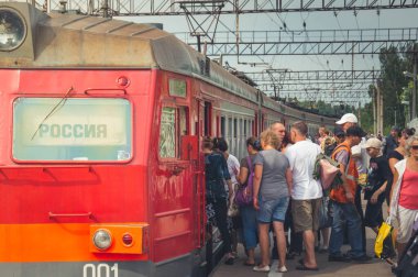 ST.-PETERSBURG, RUSSIA - 19 AUG 2013: Güneşli bir yaz gününde bir yolcu kalabalığı tren istasyonunda kırmızı trene biner. Tren kamarasındaki yazı: 
