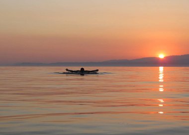 Tropikal renklerle gün batımında yüzücü.