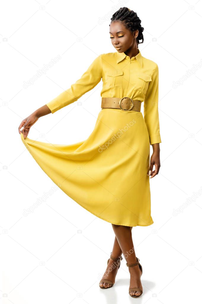 Full length portrait of attractive young african american woman with closed eyes holding end of dress isolated on white background.
