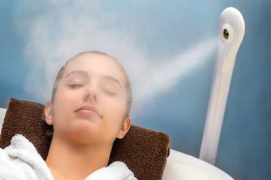 Gözleri olan genç kadın portresi yakından Termal Buhar tedavisi yüzüne sahip kapalı. Spa koltukta döşeme beyaz elbise giyen kız. 