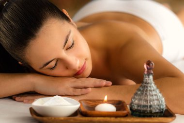 Düşük mum ışık portre rahatlatıcı spa masaj yağı ve güzellik ürün yanındaki kadının.