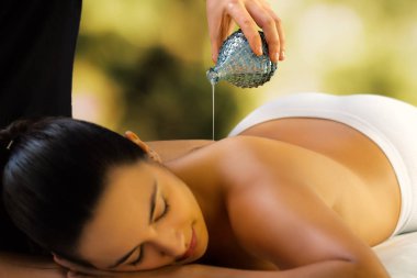 Düşük ışık Spa'da rahatlatıcı kadının kapatın. Terapist sırtına masaj yağ boşaltma.