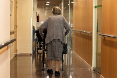 Tam uzunlukta arka görünüm, üst düzey kadın, geriatrik merkezinin koridorda yetişkin tıbbi Walker ile yürüyüş portre.