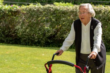 Bahçe yetişkin Walker ile rehabilitasyon yapıyor kıdemli kadının portre yakın.