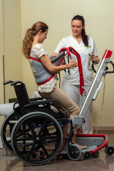 병원에서 휠체어에 리프트와 장애인 여성을 간호사의 초상화 — 스톡 사진