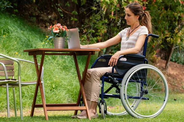 테이블에 휠체어에 여성의 초상화 가드에서 노트북에서 일하는 소녀의 측면보기 — 스톡 사진