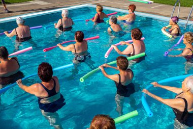 Son sınıf su sporları sınıfının arka görüntüsü. Yaşlı kadınlar köpüklü erişteyle spor yapıyor..