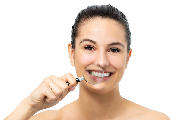 Close up portrait of young girl holding magnifying glass in front of healthy teeth. Isolated on white background.