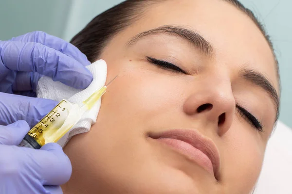 女性の顔の横に針で注射器のマクロクローズアップ 女の子に美容ホルモン治療を行うセラピスト — ストック写真