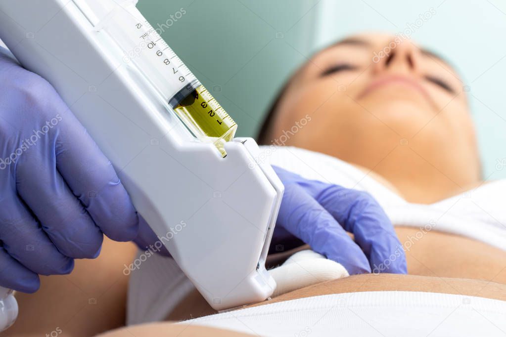 Therapist doing non-surgical cosmetic medicine treatment on female tummy with micro needle.