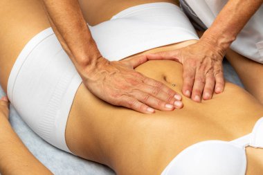 Kadın karnında manipülatif tedavi uygulayan bir fizyoterapist. Karın masajı yapan terapist bağırsak tıkanıklığını gideriyor..