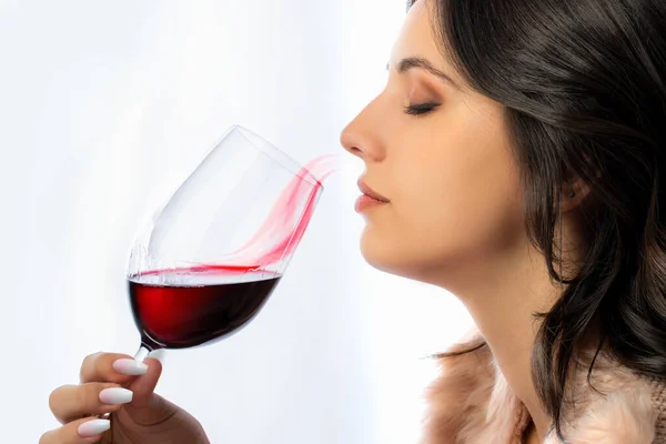 赤ワインの香りを嗅ぐ若い女性の肖像画を閉じます ガラスから鼻へと伝わる概念的な赤味がかった香りの波 — ストック写真