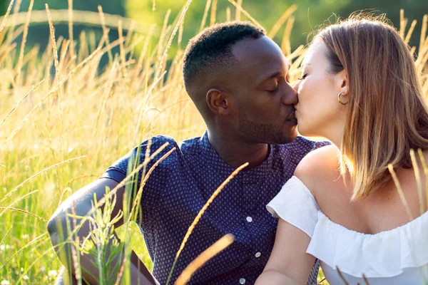 在草地上亲吻的浪漫的多种族夫妇的近照 年轻的黑人男子和高加索人女友在傍晚的阳光下 — 图库照片