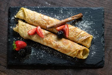 Tarçınlı ve kırmızı meyveli ince fırınlanmış krep manzarasını kapat..