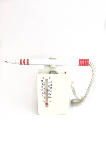 room thermometer with a fountain pen on a stand on a white background. Serves to measure the temperature in the room