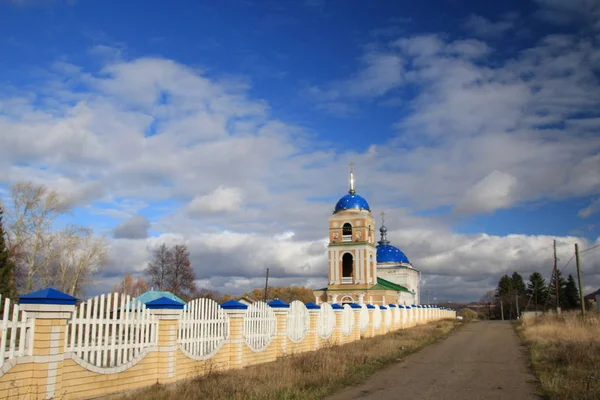 Vesnický kostel vede silnice podél plotu — Stock fotografie