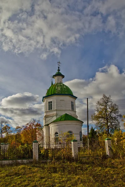 Autumn landscape with clouds over the village church — Stock Photo, Image
