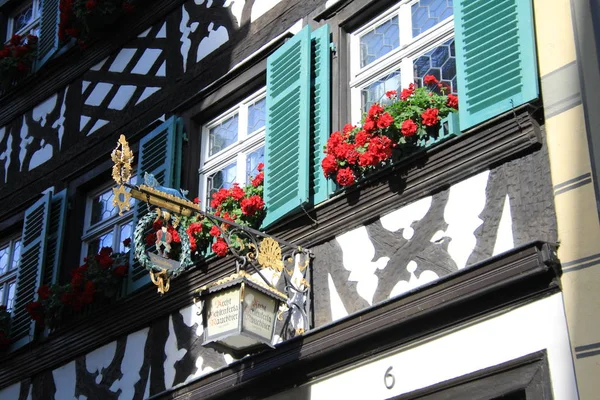 Ein Schild mit einer Laterne auf einem Metallbügel und Blumen in den Fenstern — Stockfoto