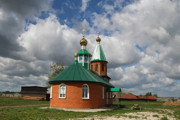 Paisaje con vistas a una iglesia rural bajo un cielo azul con nubes blancas en Chuvashia — Foto de Stock