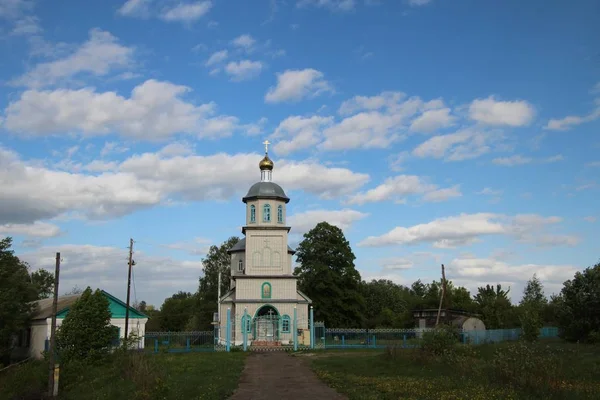 Jarní krajina s venkovským kostelem pod modrým nebem s bílými mračny ve vesnici Ukhof, Chuvašia — Stock fotografie