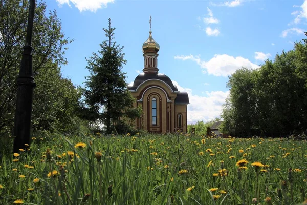Spring landscape with dandelions and a view of the temple-chapel in the city of Kanash — Stock Photo, Image