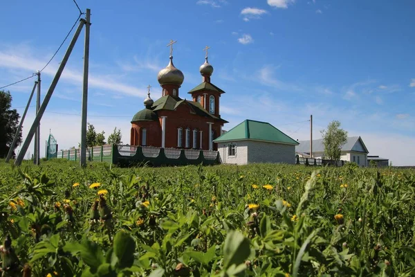 Landschaft mit Löwenzahn und Blick auf die Dorfkirche in Chuvashia — Stockfoto