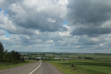 Mavi gökyüzüne karşı beyaz bulutlar ile Kırsal manzara.