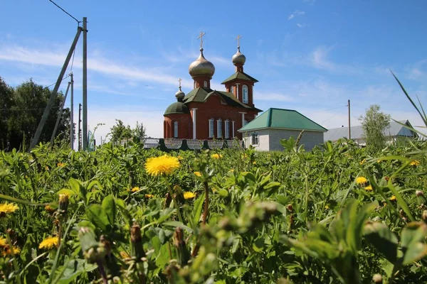 Landschaft mit Löwenzahn und Blick auf die Dorfkirche in Chuvashia — Stockfoto