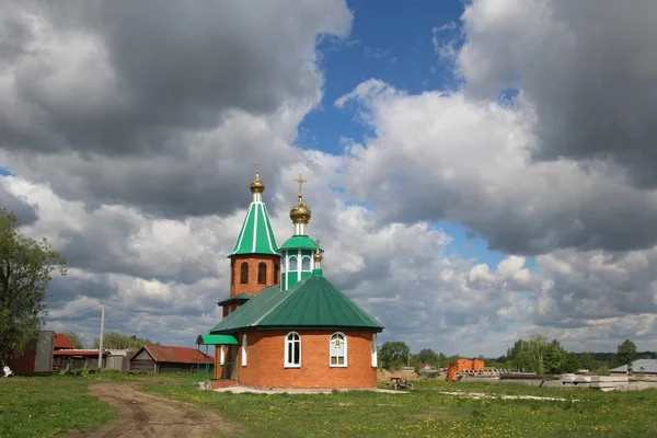 Paesaggio con vista su una chiesa rurale sotto un cielo blu con nuvole bianche a Chuvashia — Foto Stock
