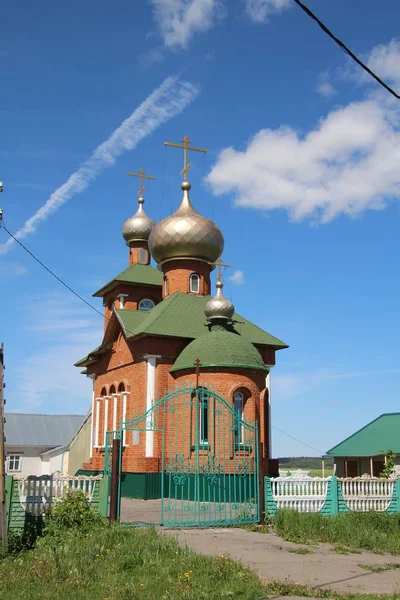 Pohled na vesnický kostel pod modrým nebem s bílými mračny ve vesnici New Shaltyama v Chuvašii, — Stock fotografie