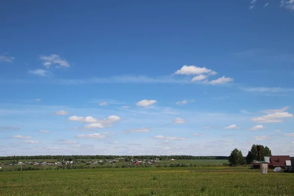 Venkovská krajina s modrou oblohou a bílými mračny na zeleném poli Stock Fotografie