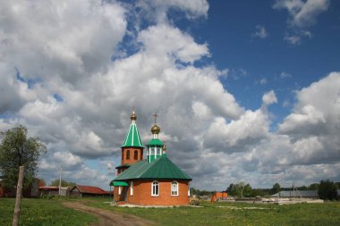 Chuvashia beyaz bulutlar ile mavi bir gökyüzü altında kırsal bir kilise manzaralı Manzara