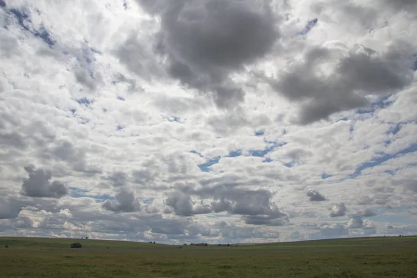 Vista do campo sob o céu azul e nuvens brancas Fotografia De Stock