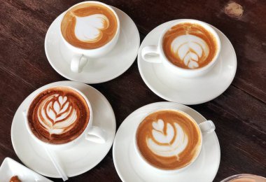 Ahşap arka planda beyaz bir fincan kahve dört fincan