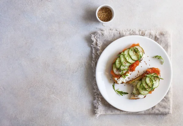 Salmon, cucumber and cream cheese rye sandwich on the wooden background, top view. Delicious snack or appetizer for wine.