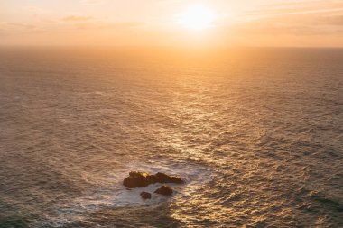 gün batımı ve sakin deniz önce güneşin turuncu renk tonu. Denizde büyük taşlar